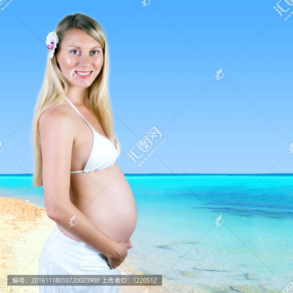 幸福的孕婦在陽光明媚的熱帶沙灘上
