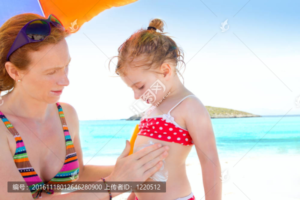 女兒和媽媽在海灘上涂防曬霜