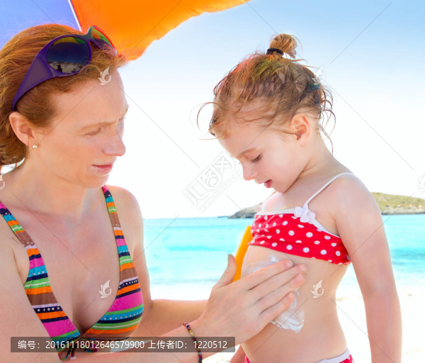 女兒和媽媽在海灘上涂防曬霜