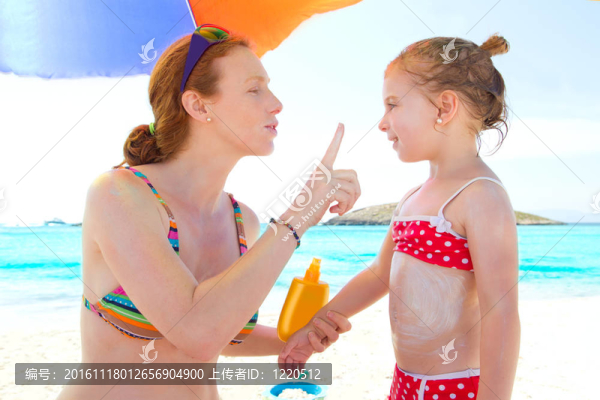 女兒和媽媽在海灘上涂防曬霜