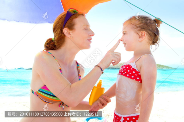 女兒和媽媽在海灘上涂防曬霜