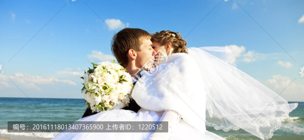 新婚夫婦在海灘上接吻。