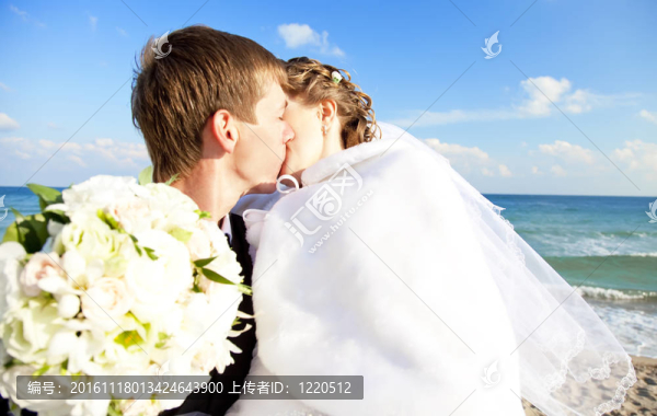 新婚夫婦在海灘上接吻。