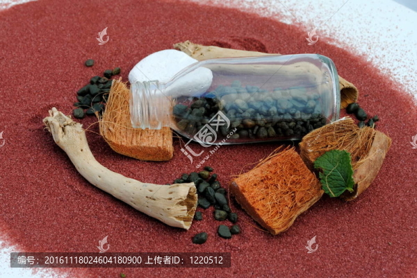 用鵝卵石和棍子鋪在紅沙子上的瓶子