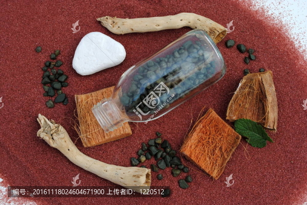 用鵝卵石和棍子鋪在紅沙子上的瓶子