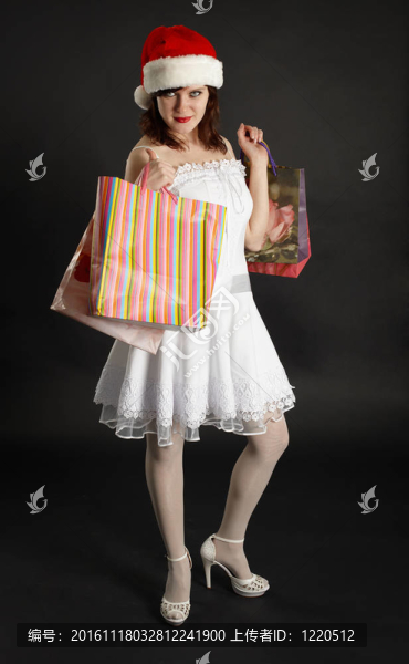 漂亮的女孩在圣誕帽與禮物在手