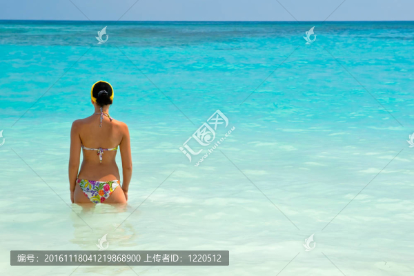 曬黑的女孩站在明亮的藍色海洋