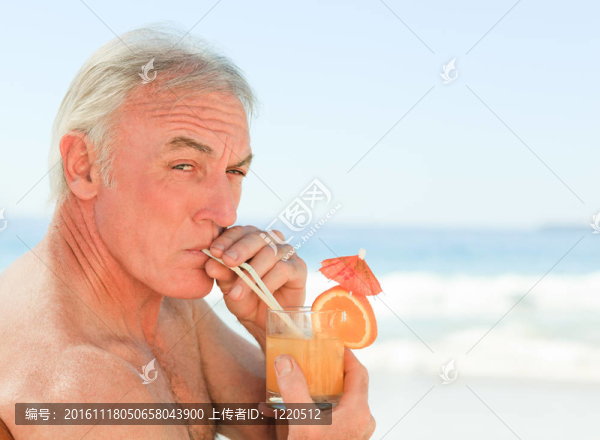 退休男子在海灘上喝雞尾酒