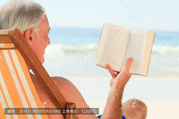 高級(jí)男子在海灘上讀一本書