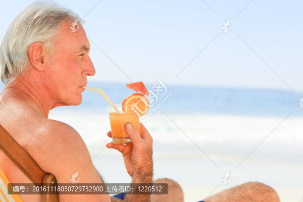 退休男子在海灘上喝雞尾酒