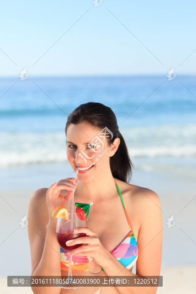 美麗的女人在海灘上喝雞尾酒