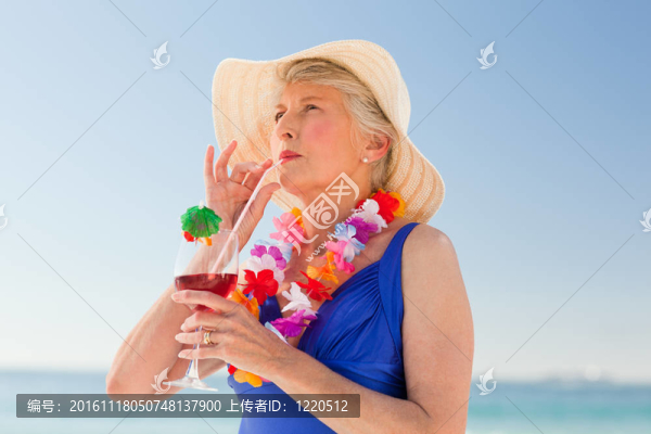 在海灘上喝雞尾酒的老年婦女