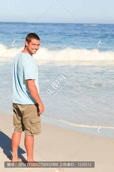 英俊的男子在海灘上散步