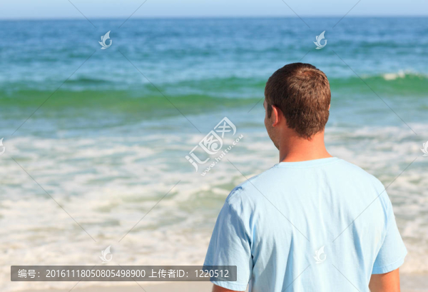 英俊的男子在海灘上散步