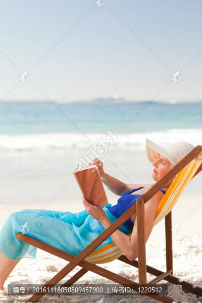 在海灘上看書的老婦人