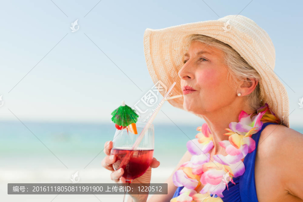 婦女在她的躺椅上喝雞尾酒