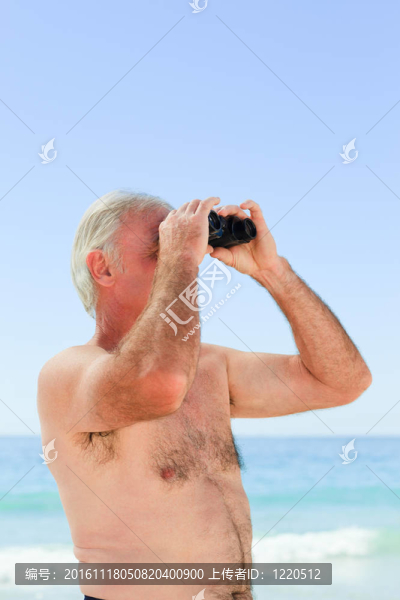 高級男子在海灘上看鳥