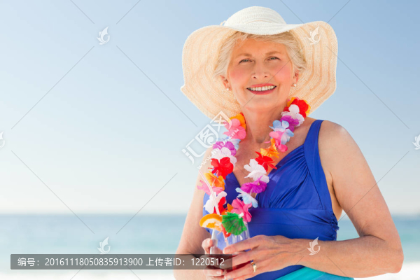 在海灘上喝雞尾酒的老年婦女