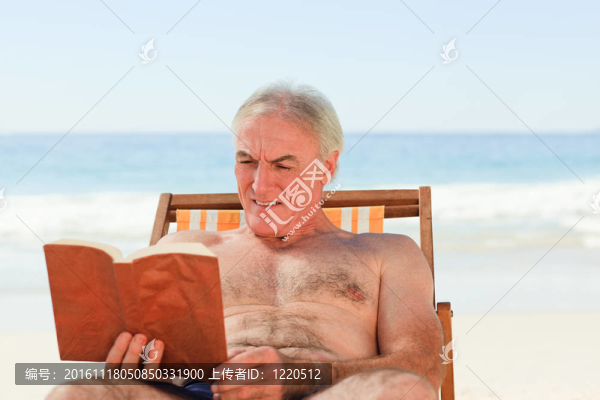 高級(jí)男子在海灘上讀一本書