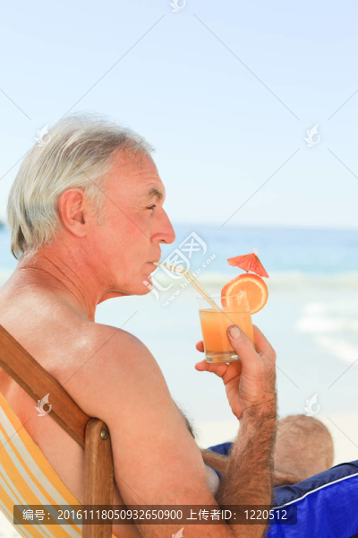 退休男子在海灘上喝雞尾酒