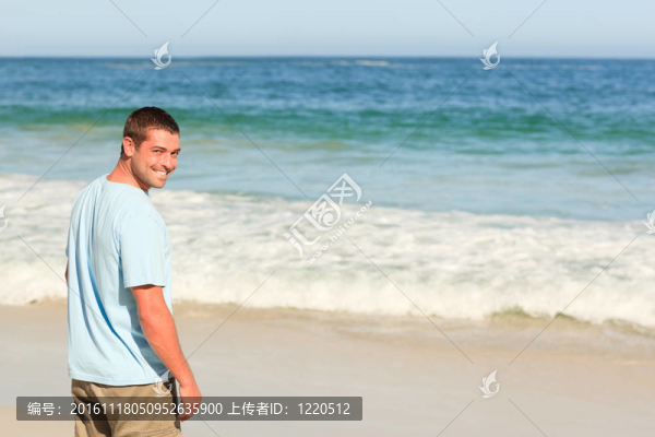 英俊的男子在海灘上散步