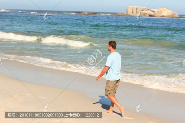 英俊的男子在海灘上散步