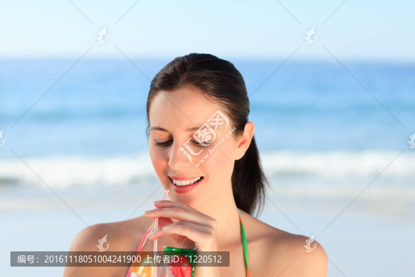 美麗的女人在海灘上喝雞尾酒