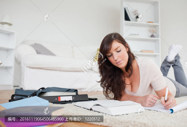 年輕漂亮的女人躺在客廳的地毯上寫在筆記本上
