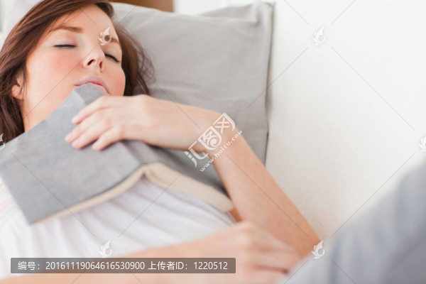 年輕漂亮的女性躺在客廳的沙發(fā)上休息看書