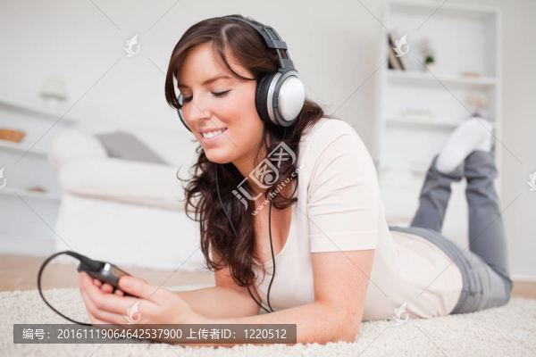 漂亮的黑發(fā)女人的MP3播放器聽音樂，趴在客廳的地毯