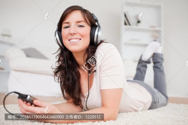 漂亮的黑發(fā)女人的MP3播放器聽音樂，趴在客廳的地毯