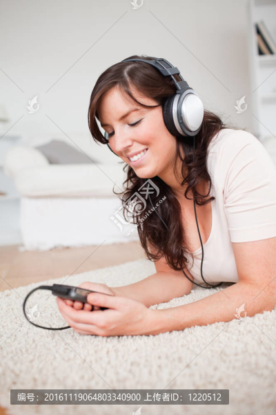 漂亮的黑發(fā)女人的MP3播放器聽音樂，趴在客廳的地毯