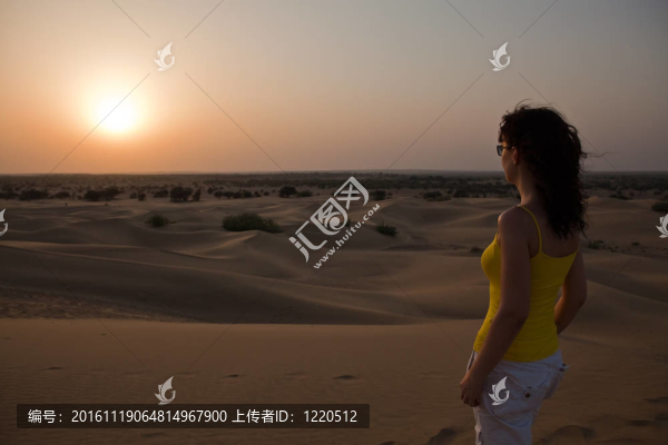 女人看著日落Khuri沙丘在塔爾沙漠附近的拉賈斯坦州杰伊瑟爾梅爾印度