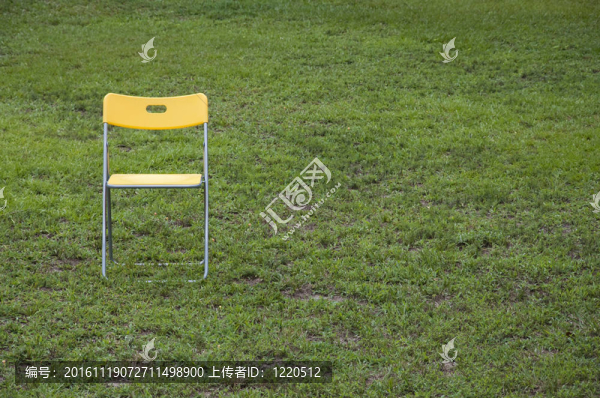 黃色的折疊椅坐在明亮的綠色草地上。