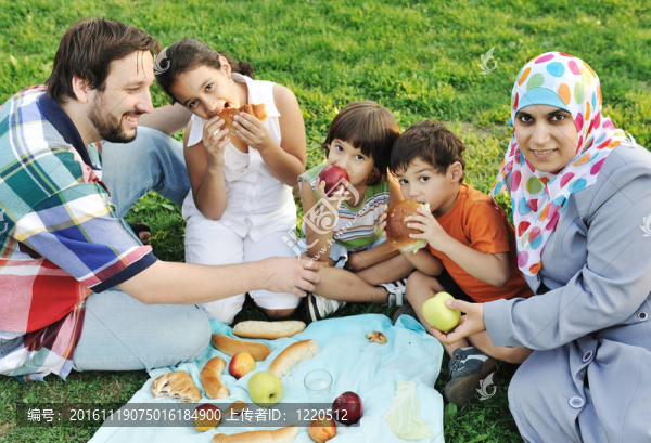 Muslim一家；母親和父親帶著三個(gè)孩子一起在大自然中坐著吃青草；野餐