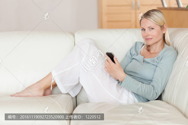 女人在沙發(fā)上用她的智能手機(jī)