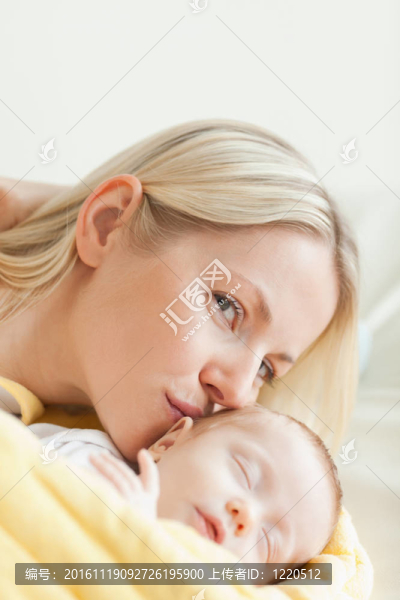 可愛的母親吻著她熟睡的嬰兒