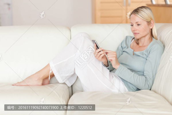 女人在沙發(fā)上打她的智能手機(jī)