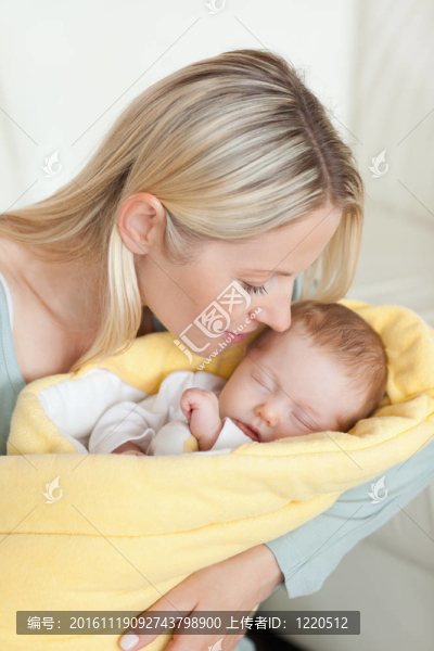 慈愛的母親在懷里親吻熟睡的嬰兒