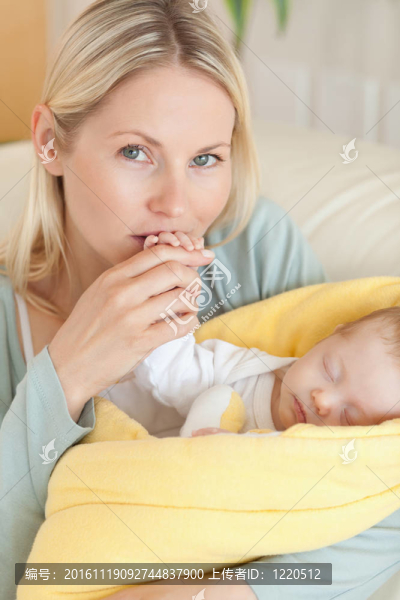 親熱的母親親吻她嬰兒的手