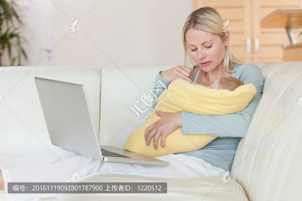 媽媽帶著筆記本在沙發(fā)上抱著她的寶貝