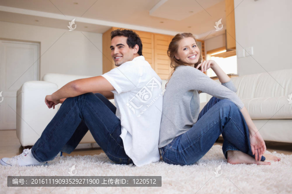 一對年輕夫婦坐在地板上背靠背