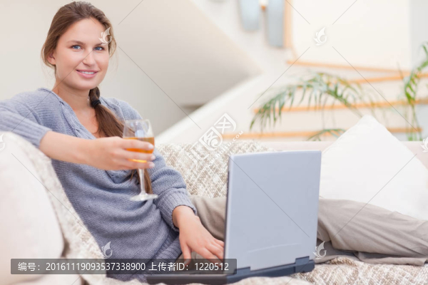 女人在使用筆記本電腦時喝了一杯酒