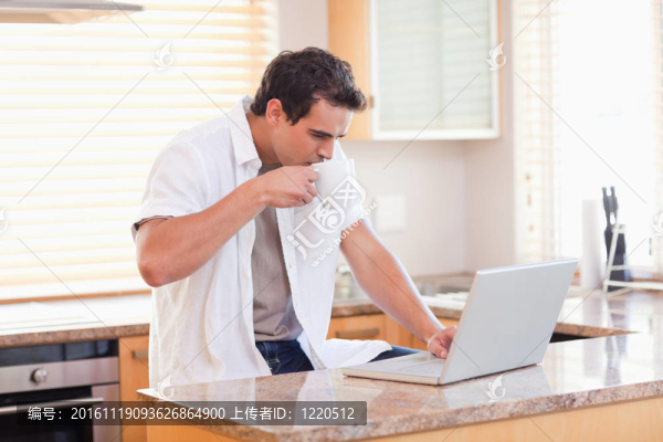 廚房里有咖啡和筆記本電腦的人