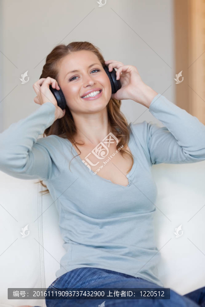 女人用耳機在沙發(fā)上聽音樂