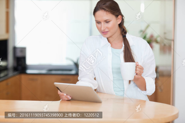 婦女喝茶時使用平板電腦