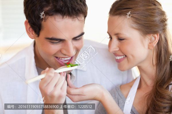 男人正在品嘗他女朋友正在做飯的飯菜