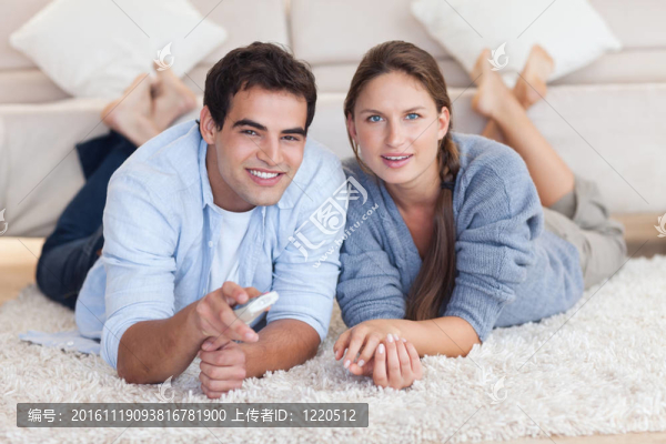 可愛(ài)的情侶躺在地毯上看電視