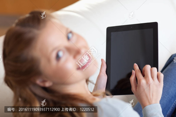 微笑的女人在沙發(fā)上使用平板