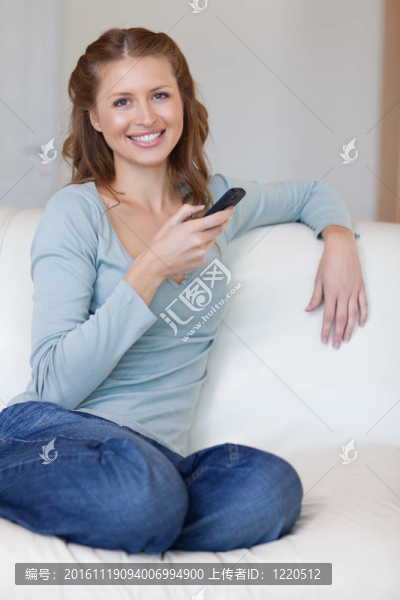 微笑的女人在沙發(fā)上打字短信